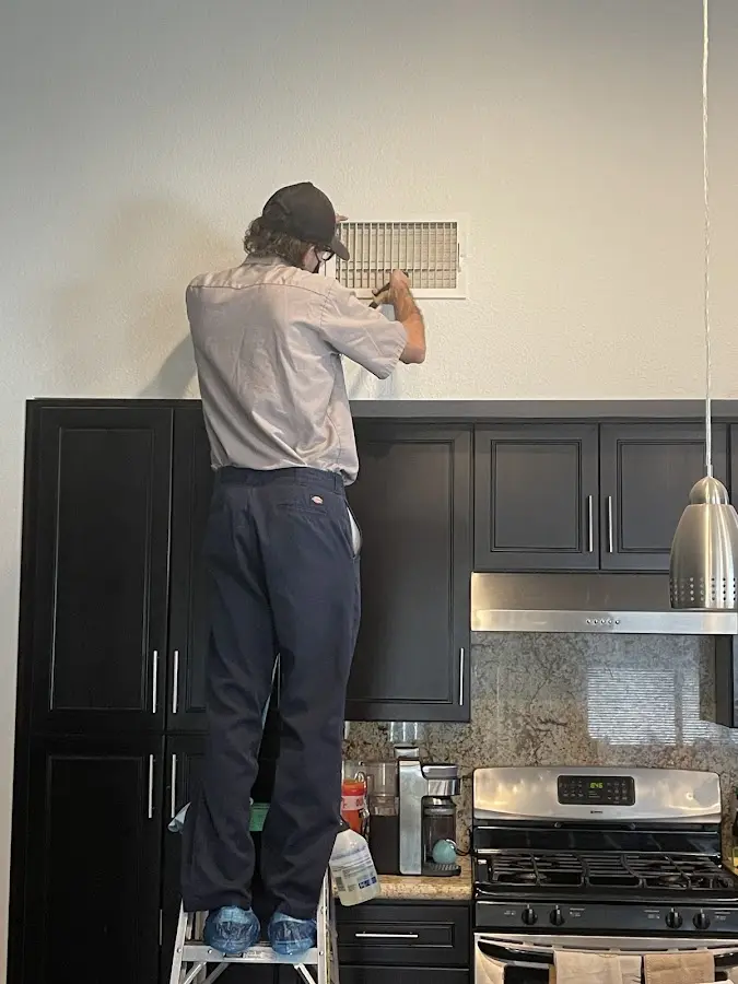 Technician inspecting an air vent during HVAC service in Claremore
